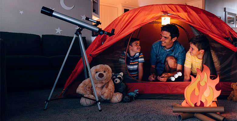 Ubezpieczenie na życie - ojciec z synami bawią się w pokoju w biwak nocą (ognisko i luneta)