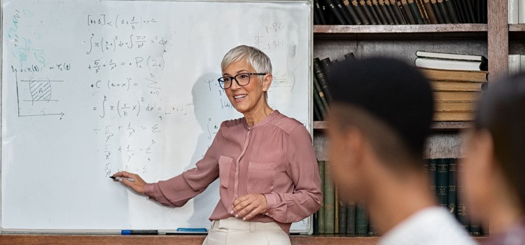Nauczaj innowacyjnie – program Innovation in Teaching - uśmiechnięta pani profesor przy tablicy