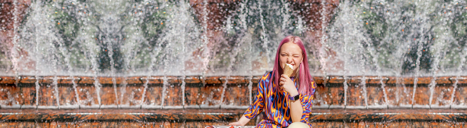 Promocja Konta Jakie Chcę dla nastolatka - dziewczynka z fioletowymi włosami siedzi na schodach i je loda